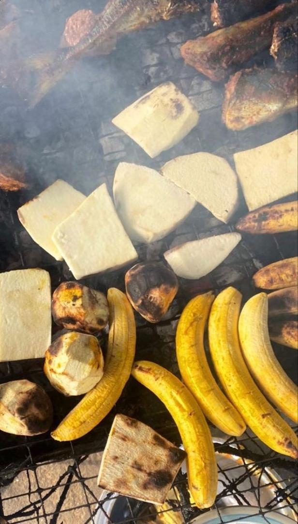 Plantain, yam and fish roasting over a smoky charcoal grill